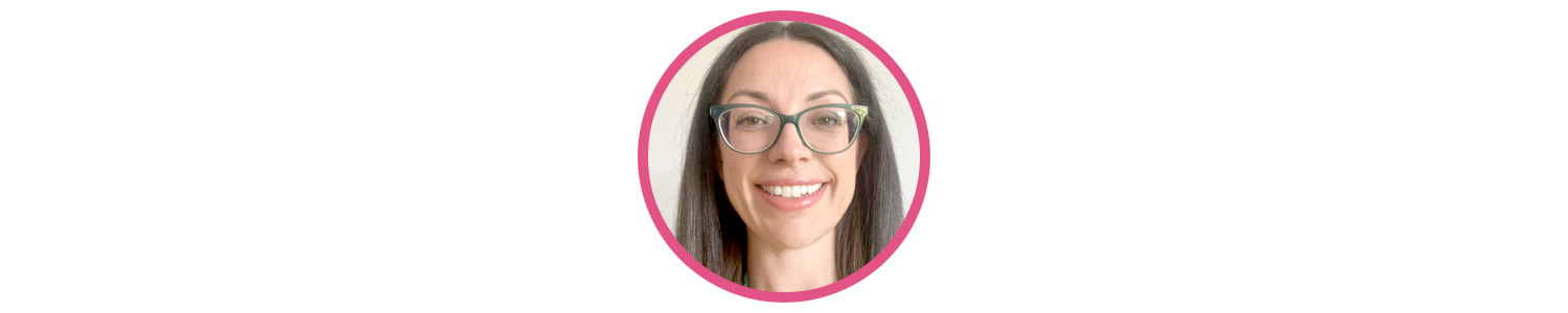 Photo of Ceri Wilcock, a white woman with long brown hair and green flared glasses. She is smiling widely at the camera.